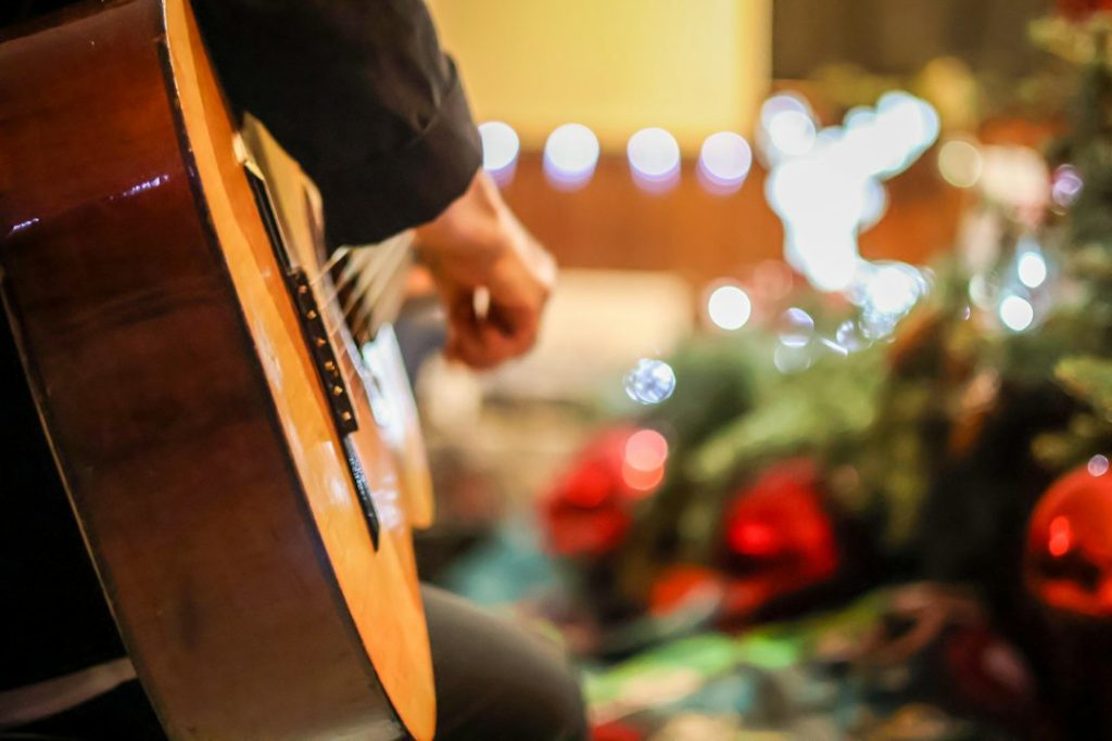 Guitarrista tocando junto a un árbol de Navidad