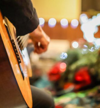 Guitarrista tocando junto a un árbol de Navidad