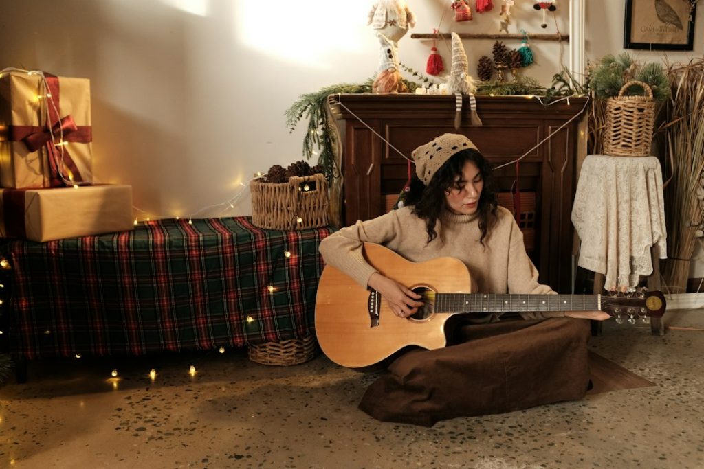 Mujer tocando guitarra junto a decoración de Navidad